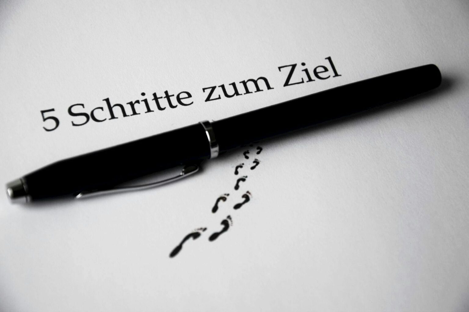 A black pen on a paper with text and footprint visual elements for a conceptual theme.